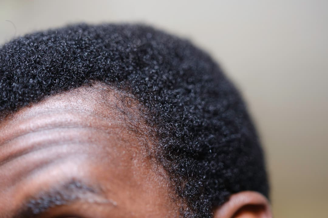 the top of a man's head, detailing his afro like hair in close up focus