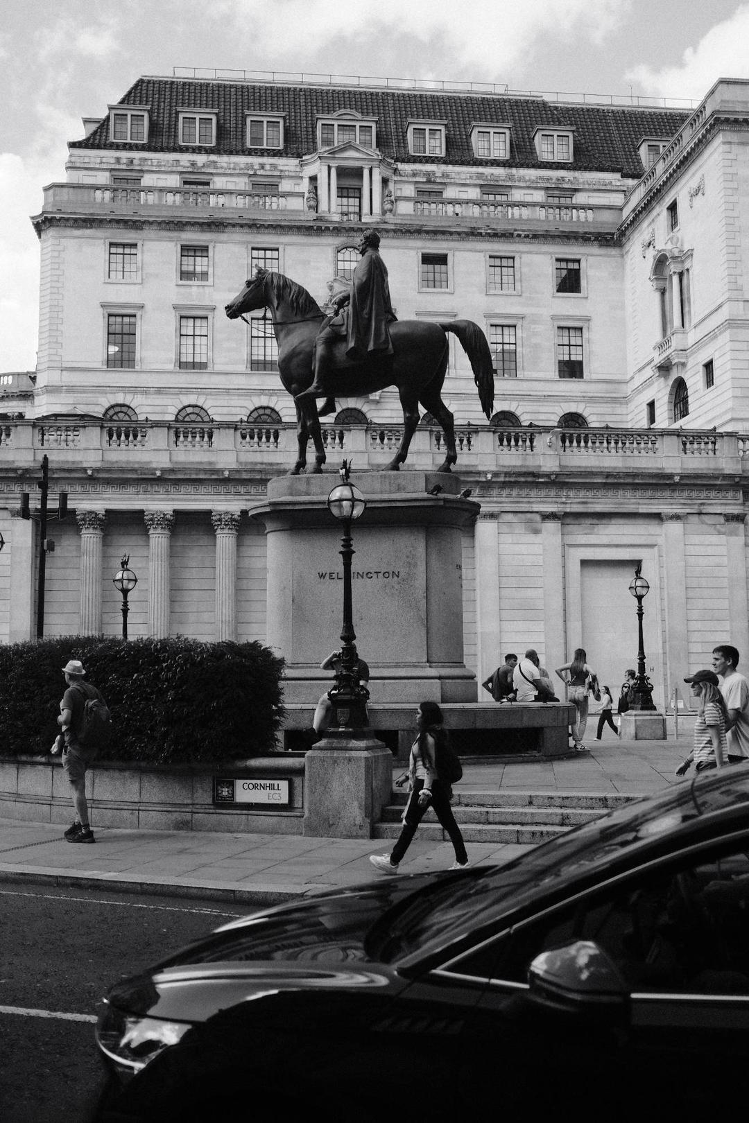 a statue of a man riding a horse in London at Cornhill, grayscale