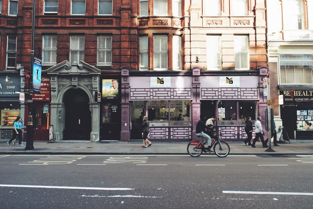 street in Soho, London in the early evening with few people walking on the pavement and one man cycling