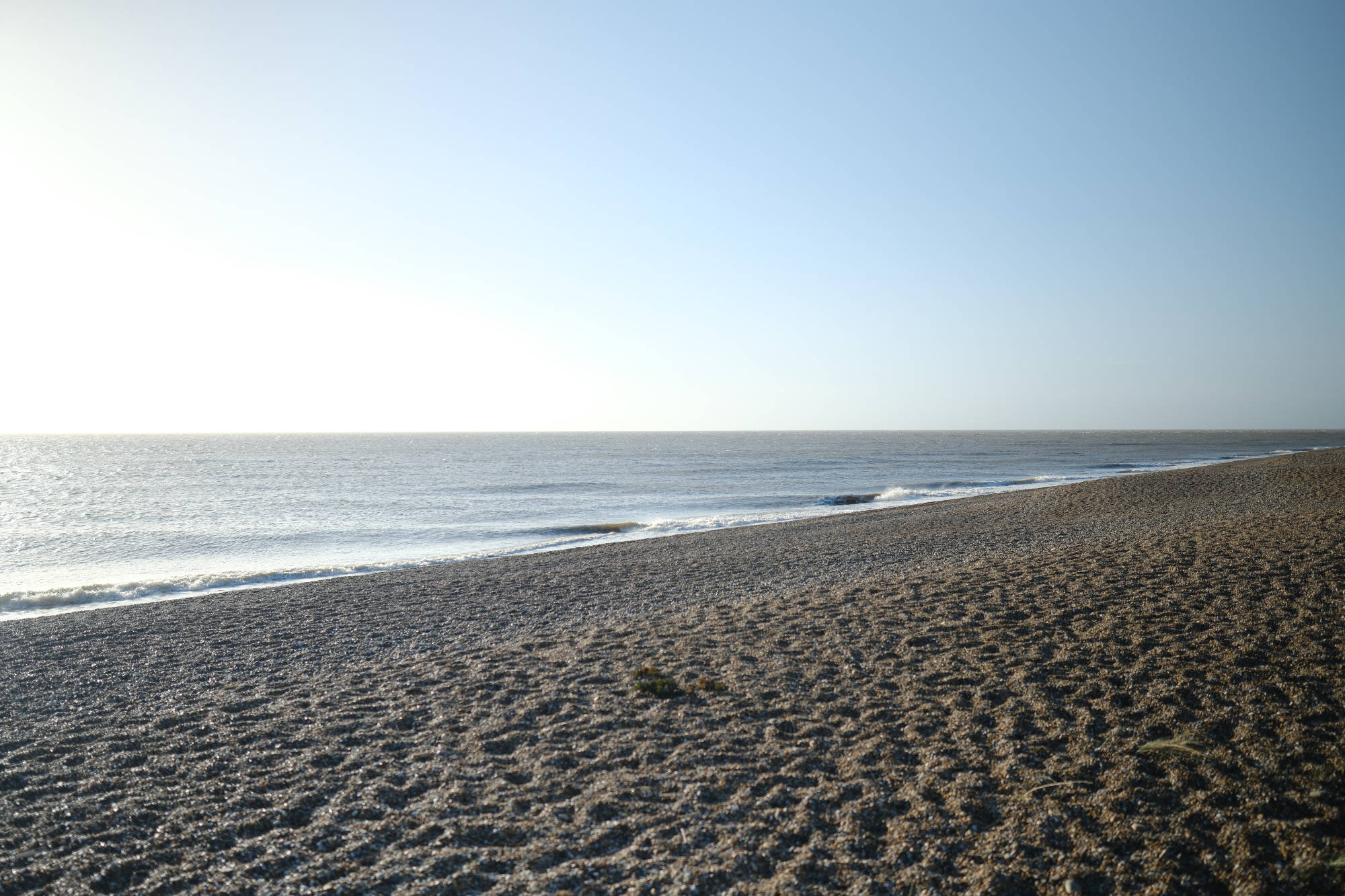 landscape view of a beach shoreline, with an overexposed (yet beautiful) blue/grey sky filling up the background